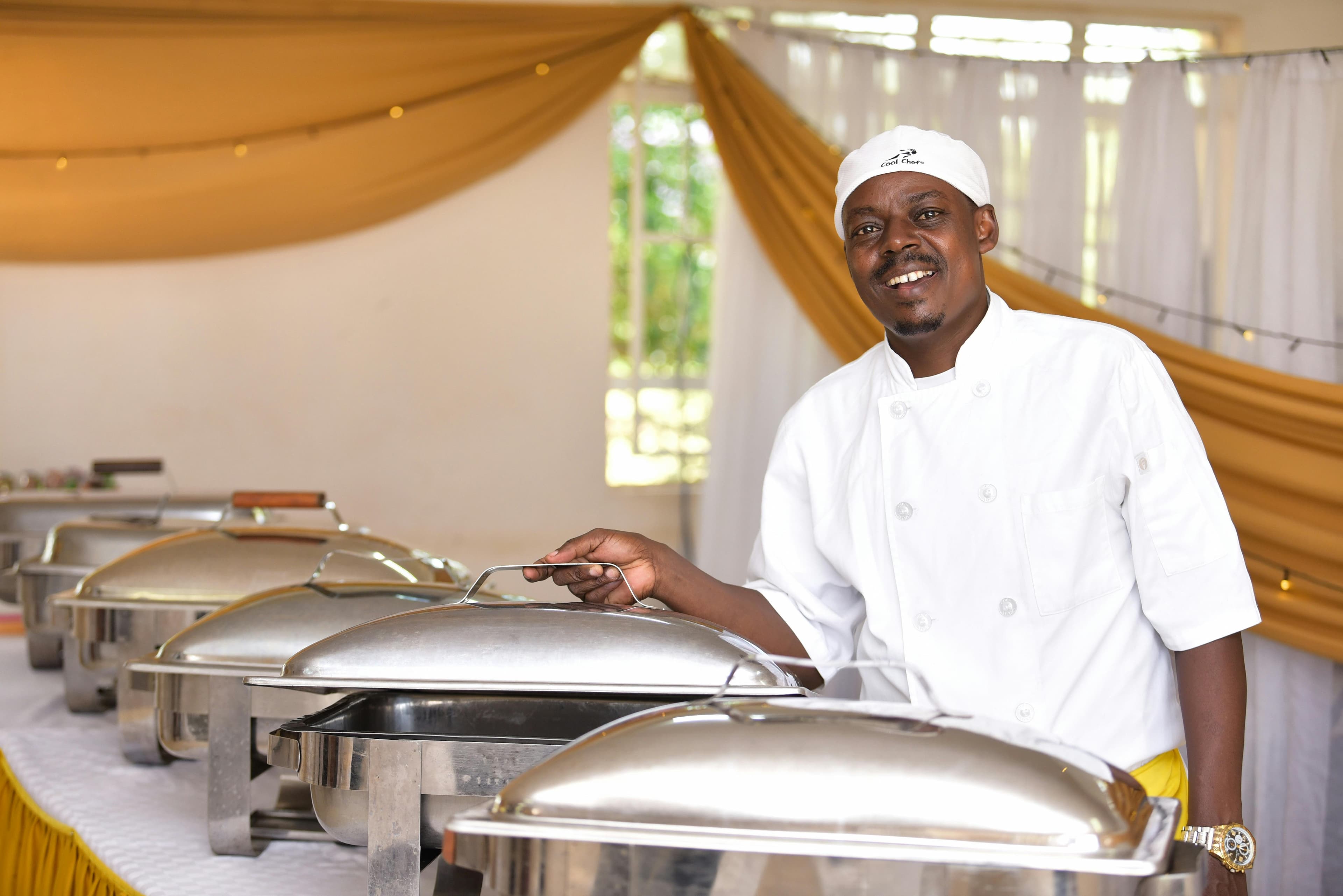 Chef standing beside a prepared buffet setup for a catered event